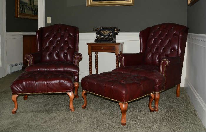 Pair of leather wing chairs with stools