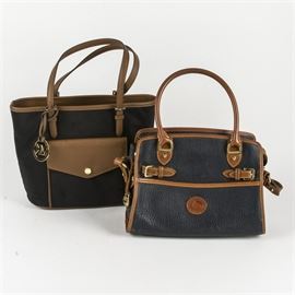 MICHAEL Michael Kors and Dooney & Bourke Purses: A pairing of MICHAEL Michael Kors and Dooney & Bourke purses. The MICHAEL Michael Kors tote features a black cloth exterior with tan leather accents. It has one snap-closure envelope style pocket on the front and two open compartments divided by a zippered compartment on the inside. A gold tone “MK” logo fob hangs from the side of one strap. “35H5GJ2T2C” is marked on a white tag inside the purse. The Dooney & Bourke satchel features a dark blue all-weather leather exterior with tan leather accents and brass hardware. The bag has a zipper closure with a small space for change and cards attached to the inside lining. A brass logo fob hangs from the zipper pull. The back of the tag inside the purse reads “A7 251239”.