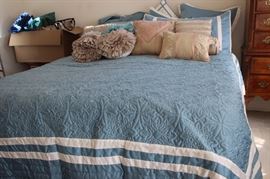 King size bed and comforter set, tons of decorative cushions.