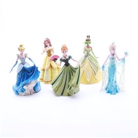 Disney Showcase Princess Figurines: A collection of princess figurines by Disney. The group of Disney princess figurines includes the following titles: “Cinderella,” “Belle,” “Elsa,” “Anna,” and “Tiana”. All of the pieces are marked either to the underside or on the box “Disney Showcase Collection” and “For decoration only”.