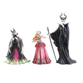 Disney's Maleficent and Sleeping Beauty Figurines: A group of Disney figurines. The selection includes two Maleficent figurines, one with a mask and a black, purple, and green cape with the serial number #4046616 printed on the bottom. The second Maleficent figurine is taller and has a cane, the serial number #4045771 is printed on the bottom. The third figurine included is a figure of Aurora from Sleeping Beauty in a pink ball gown with a masquerade mask, the serial number #4046617 is printed on the bottom.