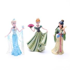 Disney Showcase Figurines, "Anna", "Elsa" and "Mulan": A set of Disney Showcase figurines. This grouping of three includes the 4045446 Elsa, the 4045772 Anna and the 4045773 Mulan. Each of these figurines depicts adult princesses in their ball gowns and are marked with branding to the underside.