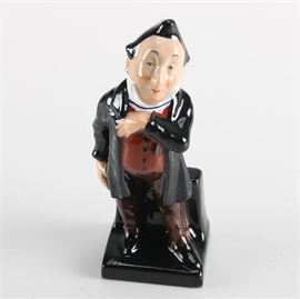 Royal Doulton Dickens Figure "Pecksniff" Circa 1960: A figure of Dickens “Pecksniff” by Royal Doulton. Featured is a vintage porcelain figure of the character Pecksniff from the Charles Dickens Series. The piece is hand-painted in tones of brown, black and white and this type of figure was produced from 1952 to 1967. A number is handwritten to the underside in black ink: “16850”.