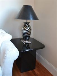 One of a pair of black lacquer end tables and zebra painted lamps