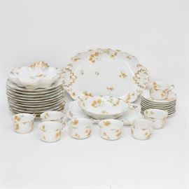 Antique China Set Including Limoges, Dufraisseix and More: An antique thirty-one piece scollection of Clifford Field Haviland and Gerard, Dufraisseix & Morel Limoges china, circa 1891-1900. The patterns feature a white ground with gilt detailing to the edges and handles, with a delicate floral pattern in a variety of gold, grey and sage tones. This collection includes a large oval and a smaller rectangular serving platter, a round serving bowl with two slight handles, a scalloped serving bowl with a single slight handle, eight cups and saucers and eleven dinner plates. The set is marked CFH/GDM France in green and Clifford Haviland Limoges in orange to the bottom.