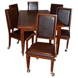 Convertible Craps and Blackjack Game Table: A convertible craps and blackjack game table. This table set includes two arm chairs and four side chairs with wood frames, brown leatherette upholstered backs and seating, fluted legs and casters. The table surface features a solid top that is removable and reversible. One side is a dining surface, the reverse side is covered in felt with a black jack table outline. You can also remove the table top completely and inside features a craps game table. Grouping also includes dice and a craps table dice stick.