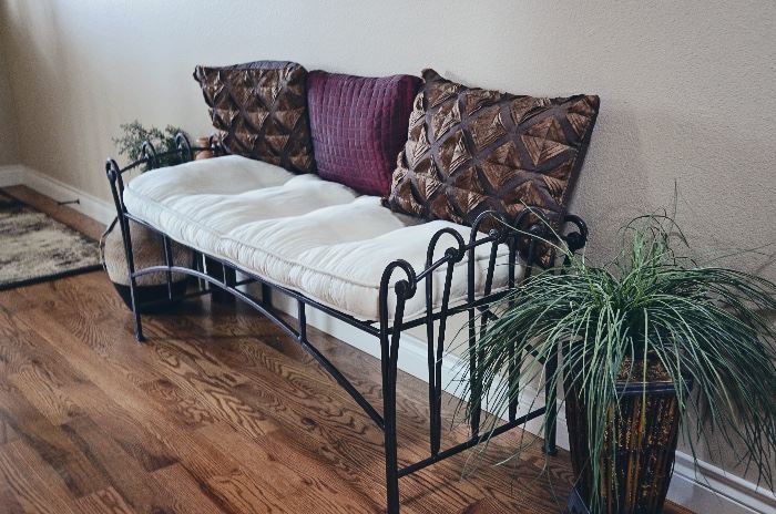 Wrought iron bench with cushion, pillows, ceramic vases, greenery