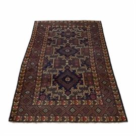 Hand-Knotted Wool Baluchi Area Rug: A hand-knotted wool Baluchi area rug. This rug features three central medallions in black, red, green, and cream on a brown backdrop. A red lattice pattern housing geometric shapes on an earthy green ground color borders the rug. Short cream fringe appear on either end of the rug. There are no maker’s marks or labels present.