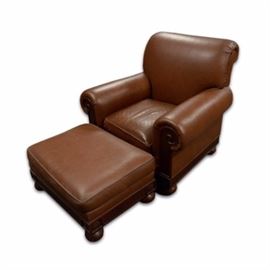 Brown Leather Chair and Ottoman by Hickory Chair: A Contemporary leather chair and ottoman with classical design accents. This brown leather chair features a rolled back and arms with an overstuffed design, a removable seat cushion and mahogany stained arm end panels with scroll carvings over a fluted apron seat rail. The piece rests on four bun feet and has a label which reads “Hickory Chair” to the interior of the seating frame. There is a coordinating rectangular ottoman to complete the collection.