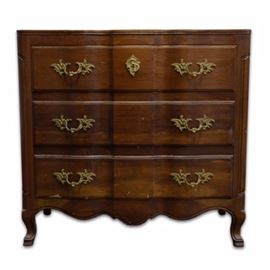 John Widdicomb Wooden Dresser With Brass Handles: A vintage John Widdicomb dresser. It features a rectangular top with a beveled serpentine front, three rows of three drawers with dovetail joinery, and decorative feet. Hardware includes cast brass floral handles and key hole.