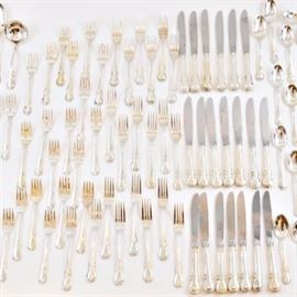 Towle Sterling Settings "French Provincial" Flatware: A collection of Towle French Provincial sterling silver flatware. The seventy-one piece set includes twenty dinner forks, twenty dinner knives with stainless blades, twenty-three teaspoons, one serving spoon, two slotted spoons, one serving fork, two ladles, a cake server with stainless blade and a cheese server with stainless blade. Each piece features the classic, fiddle-shaped handle with a border of scrolls and leaves. It is housed in a wooden chest and stand with gold tone hardware and extendable trays. The chest has top storage for flatware with two bottom drawers that are all lined in protective felt. It can be locked and includes the key. Total weight, excluding the items with stainless elements, is 98.40 ozt.