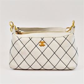 White Quilted Chanel Bag: A white quilted Chanel handbag. The shoulder bag is made of a soft white leather with black diamond stitching to the body. It features a single strap, brushed gold tone hardware, a zipper closure, logo patterned white lining and interior pockets. The serial number is 8775218. A protective bag is included.