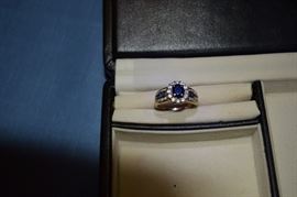 14k yellow gold oval sapphire and diamond ring. The center oval sapphire measures 7.8 X 6.5mm. The approximate carat weight is 2.0 carats and AA quality. It is encircled by 12 round diamonds approximately .50 carat weight. The ring also has 8 channel set diamonds and 4 channel set sapphires on each side of center. Total gem weight is approximately 3.0 carats.