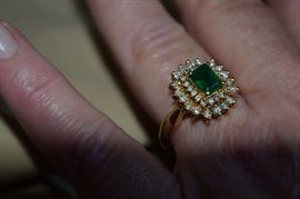 14k yellow gold emerald cut emerald and diamond ring.  The center stone measures 7 X 5.11 mm and weighs approximately 1.2 carats and is AA quality. The diamonds are I1 - I2 clarity, J color. The center stone is enhanced by 36 melle diamonds approximate total diamond weight is .61 carats. 