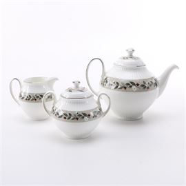 Wedgwood "Louisiana" Tea Service: A Wedgwood Louisiana tea service. This set includes a teapot, a creamer, and a lidded sugar bowl in the Louisiana pattern featuring a band of tan lines with red and white flowers with silver tone trim. The base of each item is marked “Wedgwood Bone China Made In England Louisiana”.