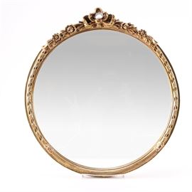 Mirror With Gilded Frame: A mirror with a gilded frame. This selection features a round wall mirror, set in a dense styrofoam molded frame with a foliate motif. The frame is painted with a gilt finish. It features hanging hardware and is labeled by Carolina Mirror to the verso.