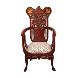 Carved Wood Arm Chair With Upholstered Seat: A carved wood armchair with upholstered seat. This armchair is made from a mahogany stained wood and has a carved cresting of foliate and scrolling design with a lighter wood floral inlay to each side of the top rail. The back splat is carved in a grass pattern, the seat has a woven cream with pink, green, and gray floral pattern.