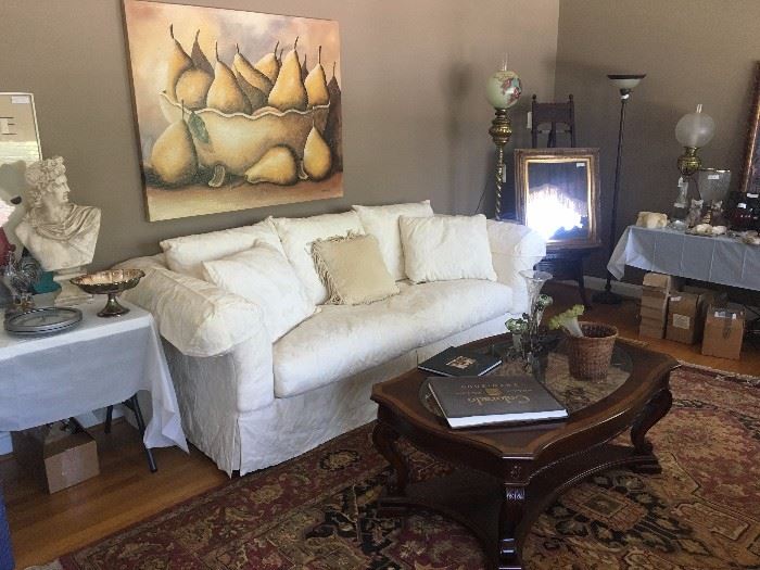 Neutral toned sofa, area rug, coffee table, original painting of still life