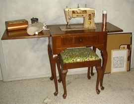 Vintage sewing machine in cabinet, stool