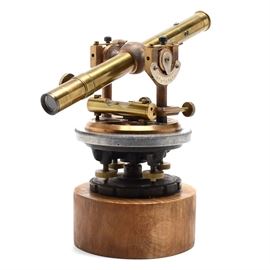 Bostrum-Brady Brass Surveyor's Transit: A brass surveyor’s transit, mounted to a curly maple plinth base. Marked “MFD By Bostrum-Brady Mfg Co., Atlanta, GA”.