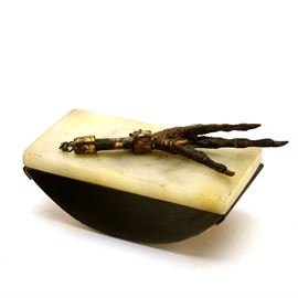 Antique Ink Blotter with Rooster Foot: An antique ink blotter with an attached rooster foot. This ink blotter features a metal bottom with refillable paper sheets, and a white marble top adorned with a rooster’s foot, attached by a bronze-toned chain.