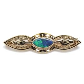 Art Deco 14K Yellow Gold Boulder Opal Enameled Bar Pin: An Art Deco 14K yellow gold bar pin featuring a boulder opal to the center with filigree sides adorned with white and black enameling.