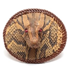 Authentic Python Head and Leather Belt Buckle: A leather and metal belt buckle faced with the authentic skin and scales of a Burmese Python. The snake has marble-like black and beige skin with red glass eye inserts, and its head rises dramatically from the face of the buckle. The piece has braided leather trim and metal buckle hardware to the verso.