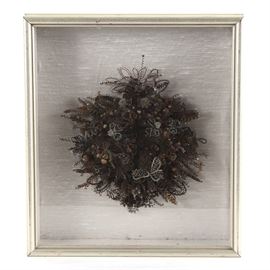 Antique Victorian Mourning Hair Wreath: An antique Victorian mourning hair wreath. During the Victorian era, it was common for family members to have a wreath or jewelry created using their deceased loved ones’ hair. This wreath features many different colors of hair, either from different stages of life for one person or from multiple people. This impressive wreath is mounted in a shadowbox with a shimmering, silky background and a silver-toned finish, presented behind glass with a hanging wire present to verso.