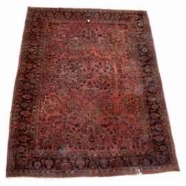 Persian Hand Woven Sarouk Style Wool Room-Sized Rug: A vintage hand woven Persian wool and cotton room-sized area rug featuring a Sarouk style. The field is a wine red with blue and white colored floral garlands, foliage, and accents. Surrounding the field, there is a dark border with alternating palmettes along with two pairs of guard borders.