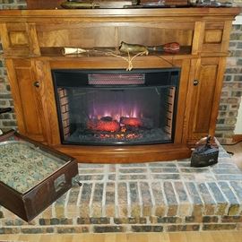 Electric portable fireplace with faux logs, heater with blower, and remote control.