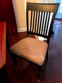 Close up of one of the dining room chairs, they are black with tan microsuede seats

