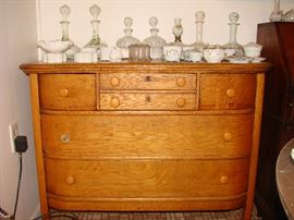 Unusual curved oak dresser covered with a collection of antique milk glass items