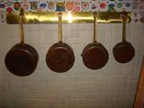 Solid copper and brass handled set of four pots with wall-mounted hanger.