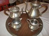 Beautifully crafted pewter tea set with coffee and tea pot and cream and sugar dispensers on a matching wood and pewter tray. The tea & coffee pots feature matching hand-carved wooden handles that match the wood insert on the tray. We don't have a date on these but there are identifying markings on the bottoms of each piece.
