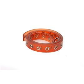 Vintage Chanel Belt: A vintage Chanel belt with a transparent burnt orange length with decorative grommet accents. The latch is marked, “CHANEL”. The belt is 34" in length.
