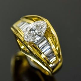 18K Yellow Gold and 1.71 CTW Diamond Cathedral Ring: An 18K yellow gold cathedral ring featuring a center tension set marquise cut diamond flanked by channel set baguette diamonds on a cathedral style shank with pierced triangle accents to the top.