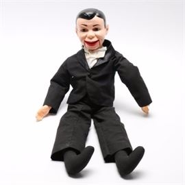 Ventriloquist's Dummy: A ventriloquist’s dummy. This dummy, depicting a male figure with dark hair, light skin and brown eyes in white-tie attire, has a molded face with a hinged mouth, molded hands and soft feet. The back of the dummy’s neck is marked “Juno Novelty Co., Inc., © 1977.”