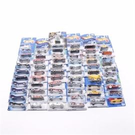 Hot Wheel Cars: A collection of Hot Wheels cars. Featured is a group of sixty-two die cast cars by Hot Wheels in original packaging. The pieces include a 2000 First Edition Mini Cooper and a 1965 Vette. There is also a 2004 First Edition Batmobile as well as a 1969 Camaro.