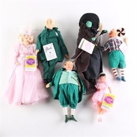 Presents Hamilton Wizard of Oz Dolls: A group of six Wizard of Oz themed dolls by Presents Hamilton. The group includes a “Ballerina Girl” doll in pink attire, a man in green and white clothing with a large pocket watch, and a “Lollipop Boy” doll in a checkered shirt with a large lollipop. Also included is a “The Wicked Witch” doll in a black cape and pointed hat, a “Wizard” doll in an all green suit, and a “Glinda” doll in a pink ball gown and crown.