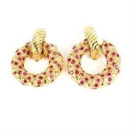 Yves Saint Laurent Gold Tone Door Knocker Earrings: A pair of vintage Yves Saint Laurent door knocker earrings. Each features a gold tone textured circle embellished with flush set pink rhinestones dangling from a twisted clip-on closure. The verso of each earring is marked “YSL” and “Made in France”.