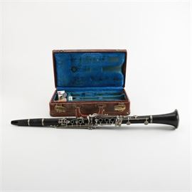 Vintage Noblet N Model Clarinet and Case: A vintage Noblet N model clarinet with a Grenadilla wood body, a black stained finish and silver plate brass alloy keyholes, levers and cups. The instrument is marked “N Noblet, Paris” to its barrel and comes with a faux brown leather case lined with a blue felt fabric.