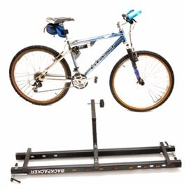 Giant ATX 980 Mountain Bike and Bike Rack: A Giant mountain bike and bike rack. The Giant aluminum full-suspension bicycle is marked “ATX 980” and “Giant CU92”. It comes with Time clipless pedals, Shimano Deore components, a Rock Shox fork, a San Marco seat and a seat sack. The rack is a Backpacker with attached caution lights. This bike model was released in 1996 and 1997.