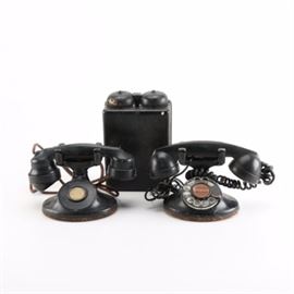 Antique Rotary Phones: A group of antique rotary phones. The group includes two all black rotary phones, one of which is connected to a large black case with bells.