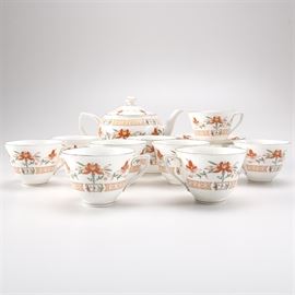 Royal Worcester "Chamberlain" Tea Set: A Royal Worchester Chamberlain tea set.This collection of seventeen pieces includes one teapot with lid, nine teacups, and seven saucers. This contemporary set was originally designed for Prince Regent in 1811. The set depicts an orange and yellow lotus flower with gilt trim. They are marked “1967 Royal Worcester Chamberlain” to the base.