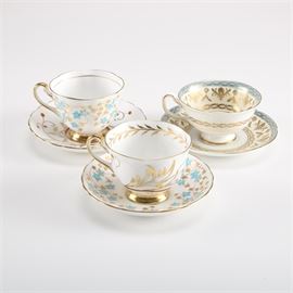 Collection of English Bone China Tea Cups and Saucers: A collection of English bone china tea cups and saucers. This grouping includes two Royal Chelsea tea cups and saucers, each having a light blue and gold-tone floral pattern. Both pieces are marked to the bottom “Royal Chelsea English Bone China Made in England”. Also offered is a Royal Grafton bone china tea cup and saucer in a cream, teal, and gold-tone foliate pattern. This piece is marked to the underside “Royal Grafton Fine Bone China Made in England”.