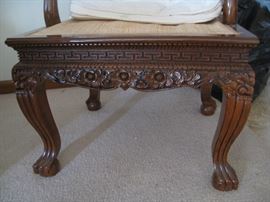 Close up of ornate carved chair with a geometric Greek like design above a floral design skirt
