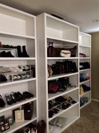 Many shoes, purses, and t-shirts; tall white shelf units