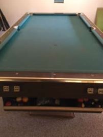 old pool table with cues and balls