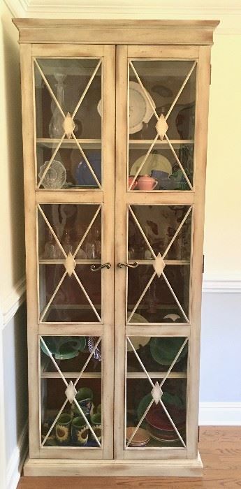 This French-country-styled lighted curio with multiple shelves and French doors is in perfect condition, and its light color and tall, narrow profile accentuate its appeal