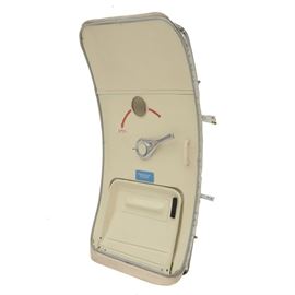 Airplane Door: A detached jet airplane door, with a curved shape, in metal with a white finish. It has a small central porthole, a lever in silver tone metal for manually opening the door, and pressure seals around the edges. By Northwing Accessories Composites Corp.